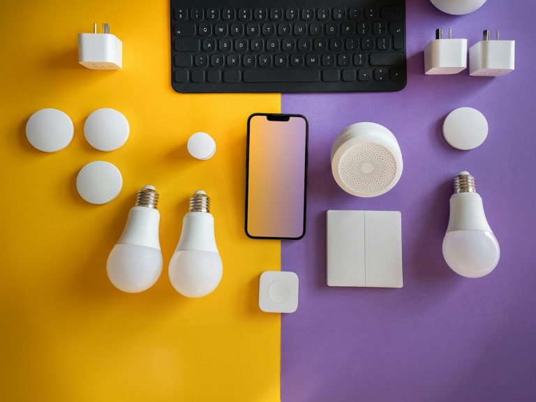 Smart devices and accessories arranged on a yellow and purple background, including bulbs and a phone.